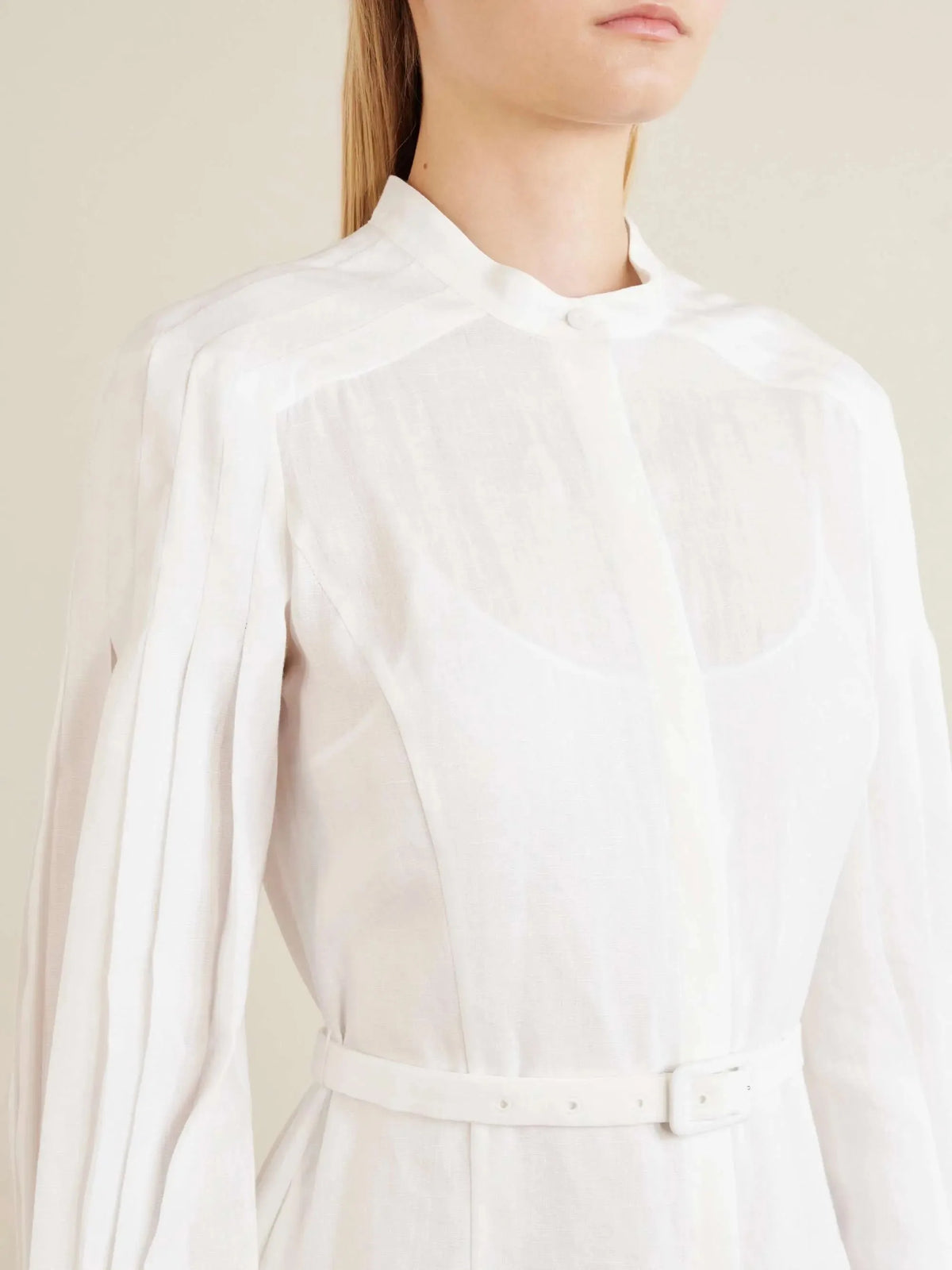 Close-up of the white linen dress showing the mandarin collar, button front and self-tie waist belt detail