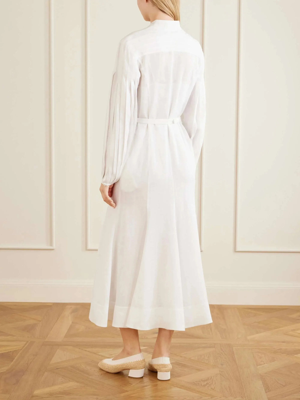 Back view of the belted white linen midi dress showing the gathered sleeves and flared midi skirt silhouette