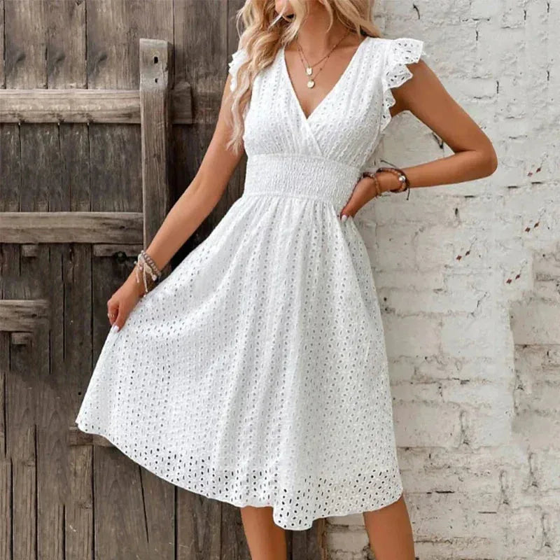 Woman modelling a white eyelet midi dress with hand on hip, showing the full A-line skirt