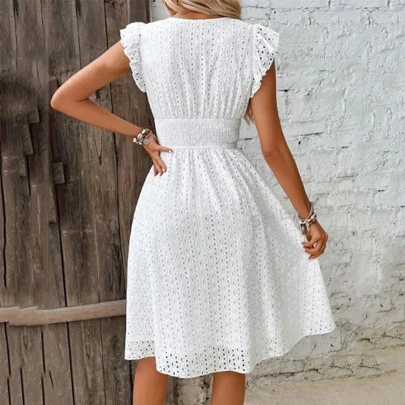 Back view of the white broderie anglaise dress highlighting the smocked waist panel and ruffle cap sleeves