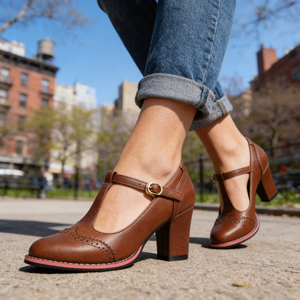 Brown leather T-strap brogue heels with contrast pink midsole shown on crossed ankles outdoors