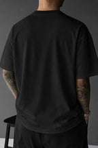 Back view of black oversized tee showing the plain ribbed crewneck and relaxed drop-shoulder silhouette