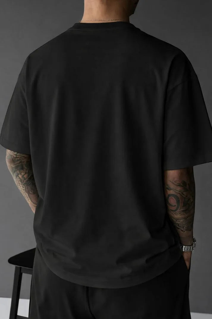 Back view of black oversized tee showing the plain ribbed crewneck and relaxed drop-shoulder silhouette