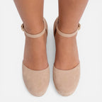 Front view of feet in beige closed-toe espadrille wedges with slim ankle straps