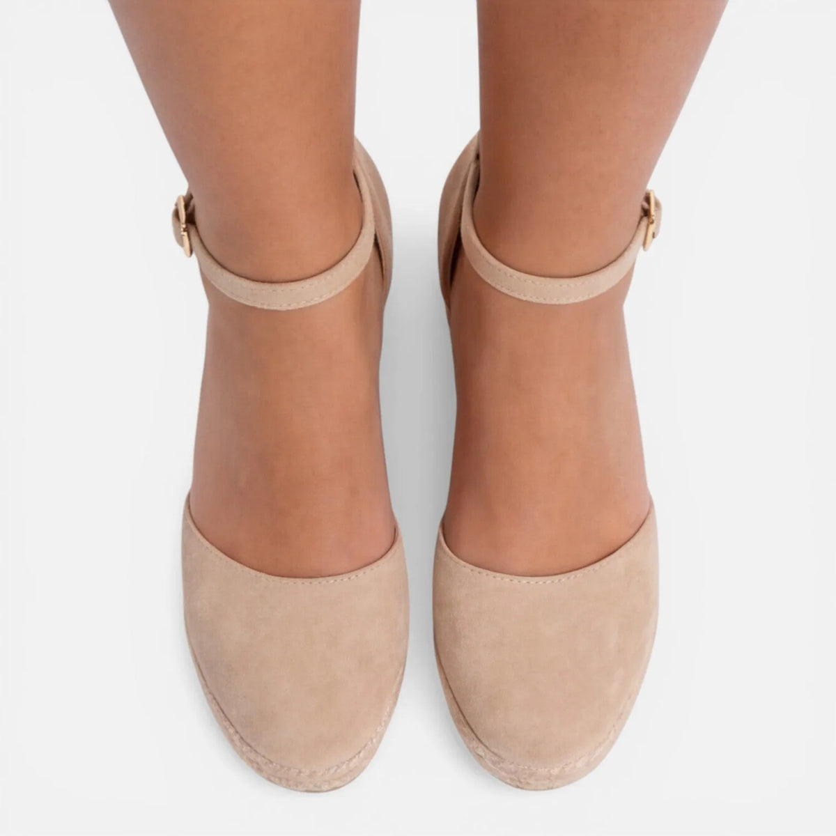 Front view of feet in beige closed-toe espadrille wedges with slim ankle straps