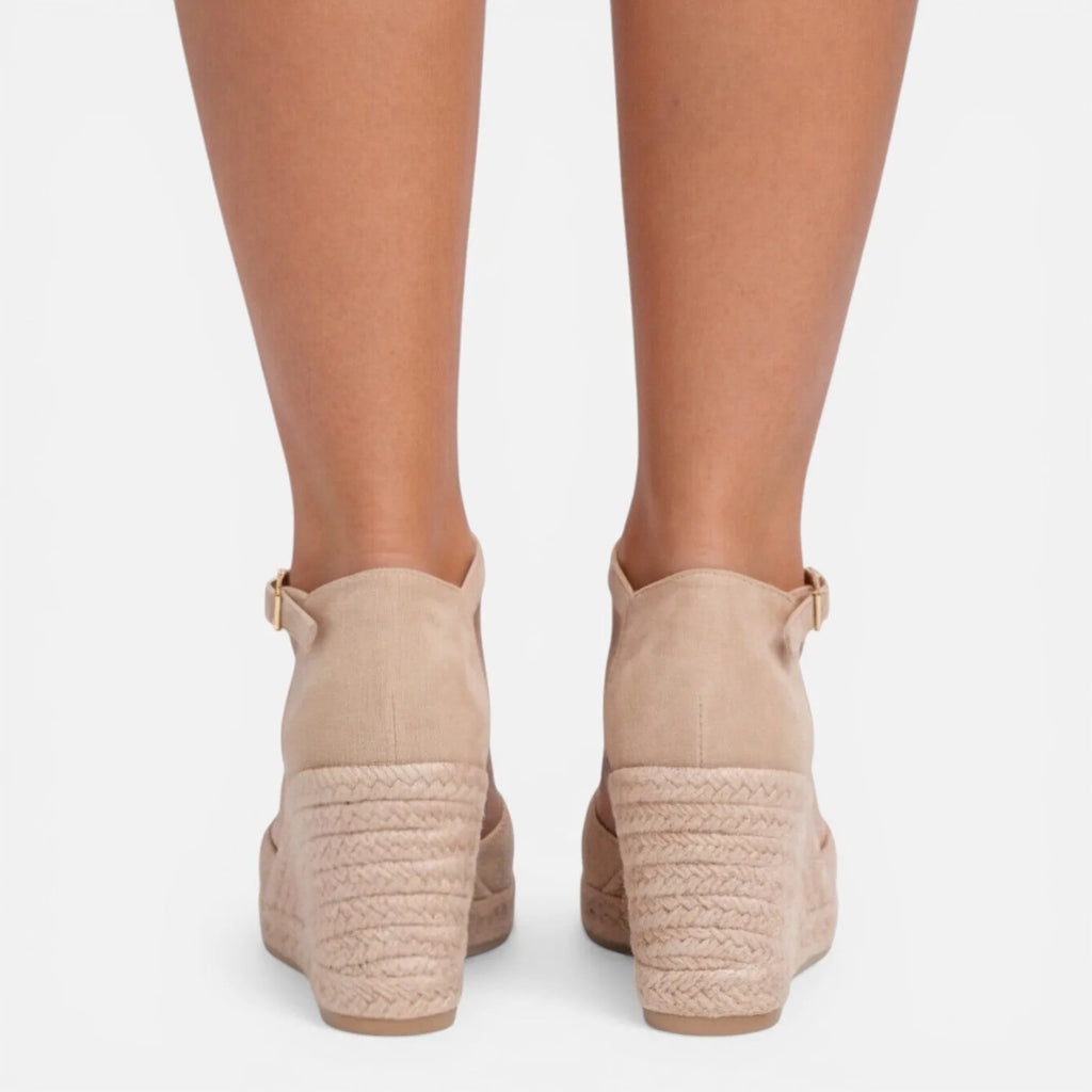 Back view of feet in beige espadrille wedges highlighting the jute wedge construction