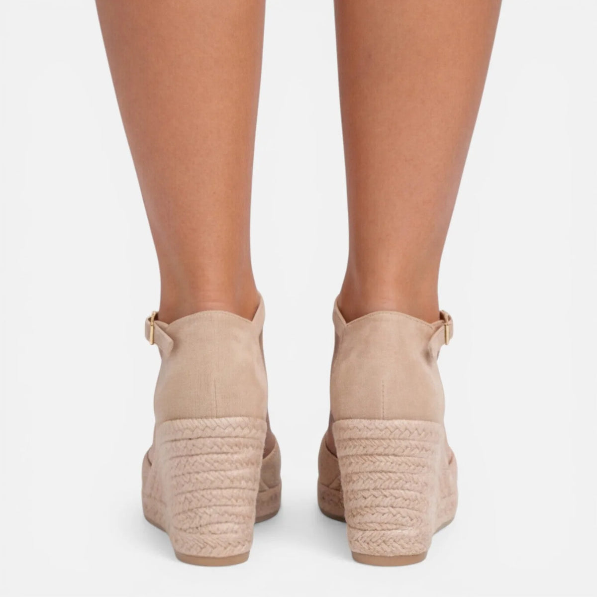 Back view of feet in beige espadrille wedges highlighting the jute wedge construction