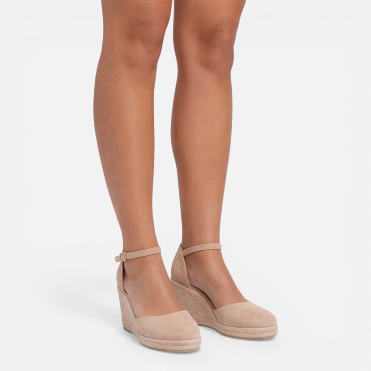 Front angled view of beige espadrille wedges showing closed-toe silhouette and ankle strap detail