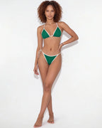 Model posing with hand on hip wearing a navy triangle bikini with white contrast edges