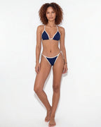Full-length front view of model wearing navy triangle bikini with tie-side bottoms against a white backdrop