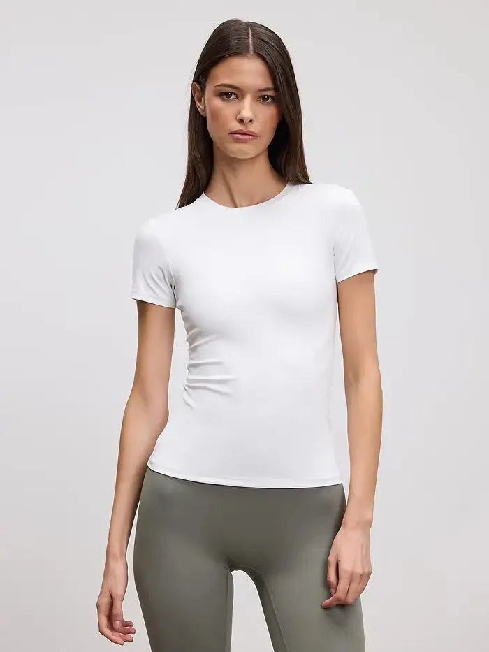 Front view of a woman wearing a fitted white crew neck tee tucked into olive green leggings