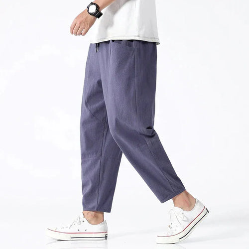 Side view of model walking in slate blue-grey cropped linen pants paired with a white t-shirt and white sneakers