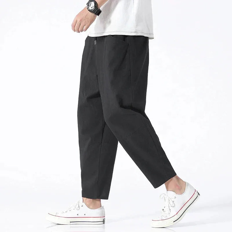 Side profile of model wearing black cropped linen pants with a white t-shirt, drawstring waist visible
