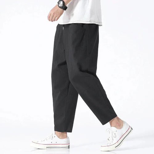Side profile of model wearing black cropped linen pants with a white t-shirt, drawstring waist visible