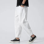 Side view of model in white cropped linen pants worn with a black t-shirt and black sneakers