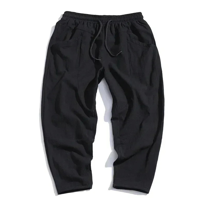 Flat lay back view of black cropped linen pants showing elastic drawstring waistband and side pockets