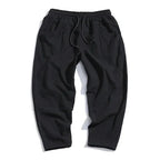 Flat lay back view of black cropped linen pants showing elastic drawstring waistband and side pockets