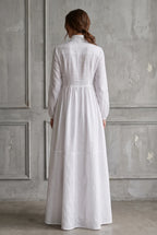 Back view of the white maxi dress showing its panelled construction, long sleeves and gathered full skirt.