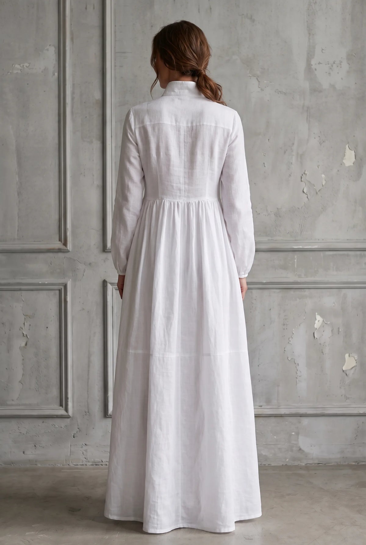 Back view of the white maxi dress showing its panelled construction, long sleeves and gathered full skirt.