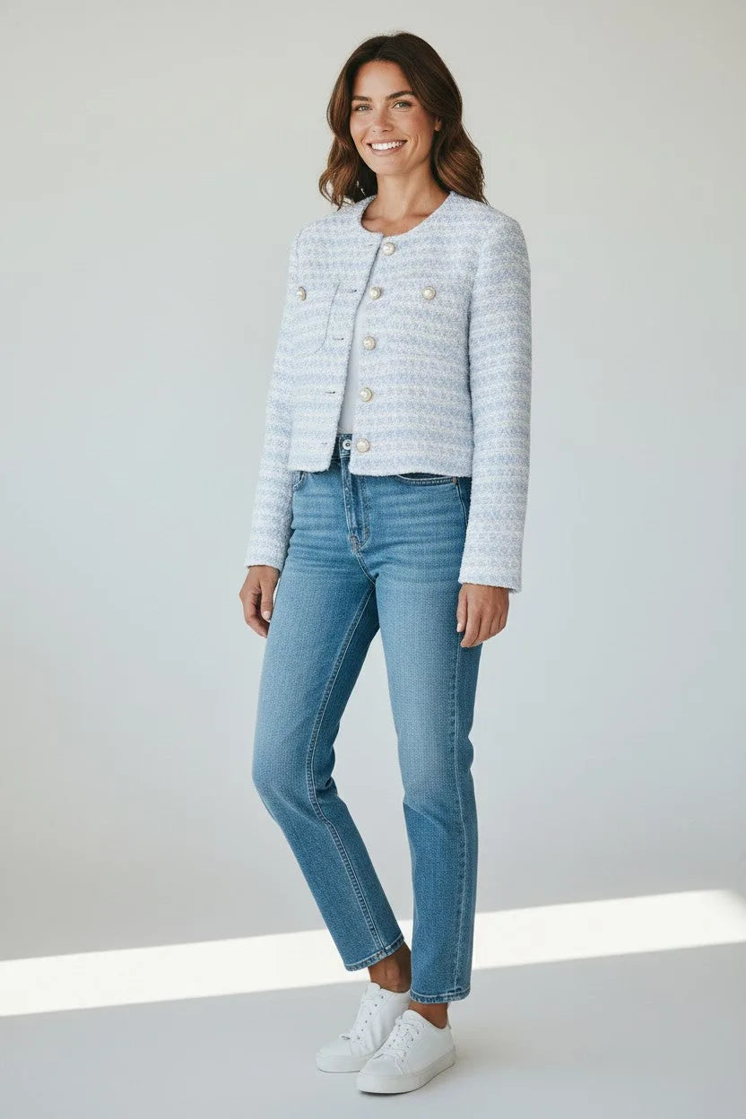 Woman wearing a cropped powder blue boucle jacket with pearl buttons over jeans and a white tee, front view.