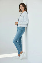 Close side profile showing the collarless neckline and pearl button detail on the cropped knit jacket.