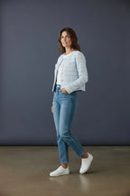 Woman walking in the cropped blue and white tweed-style jacket, showing the fitted sleeves and hem length.