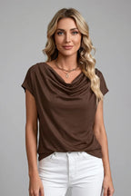 Woman wearing the brown draped cowl neck top with white jeans and a gold chain necklace, front view