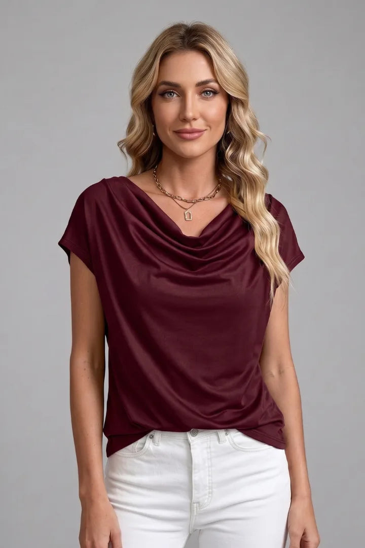 Woman modelling the burgundy draped front top with a cowl neckline and white jeans