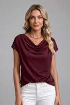 Woman modelling the burgundy draped front top with a cowl neckline and white jeans