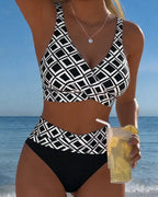 Front view of a black and white geometric print wrap bikini set with high-waisted bottoms against the ocean