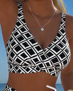 Close-up of the black and white diamond print wrap top showing the crossover V-neckline and wide shoulder straps
