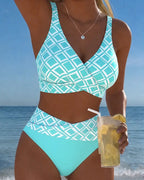 Front view of a turquoise and white geometric print wrap bikini set with high-waisted bottoms by the sea