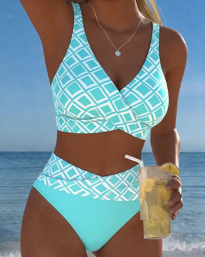 Front view of a turquoise and white geometric print wrap bikini set with high-waisted bottoms by the sea