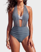 Model holding a drink on the beach wearing the black high-waisted bikini with mesh side panel