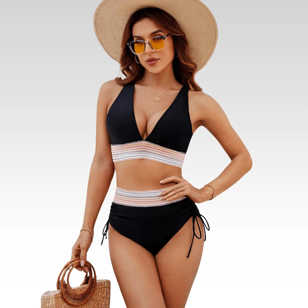 Front view of a black high-waisted bikini with a deep V-neck top and striped zigzag trim, styled with a sun hat and straw bag