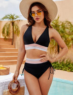 Close-up front view of the black bikini set showing the plunging halter top and colourful striped waistband by the poolside