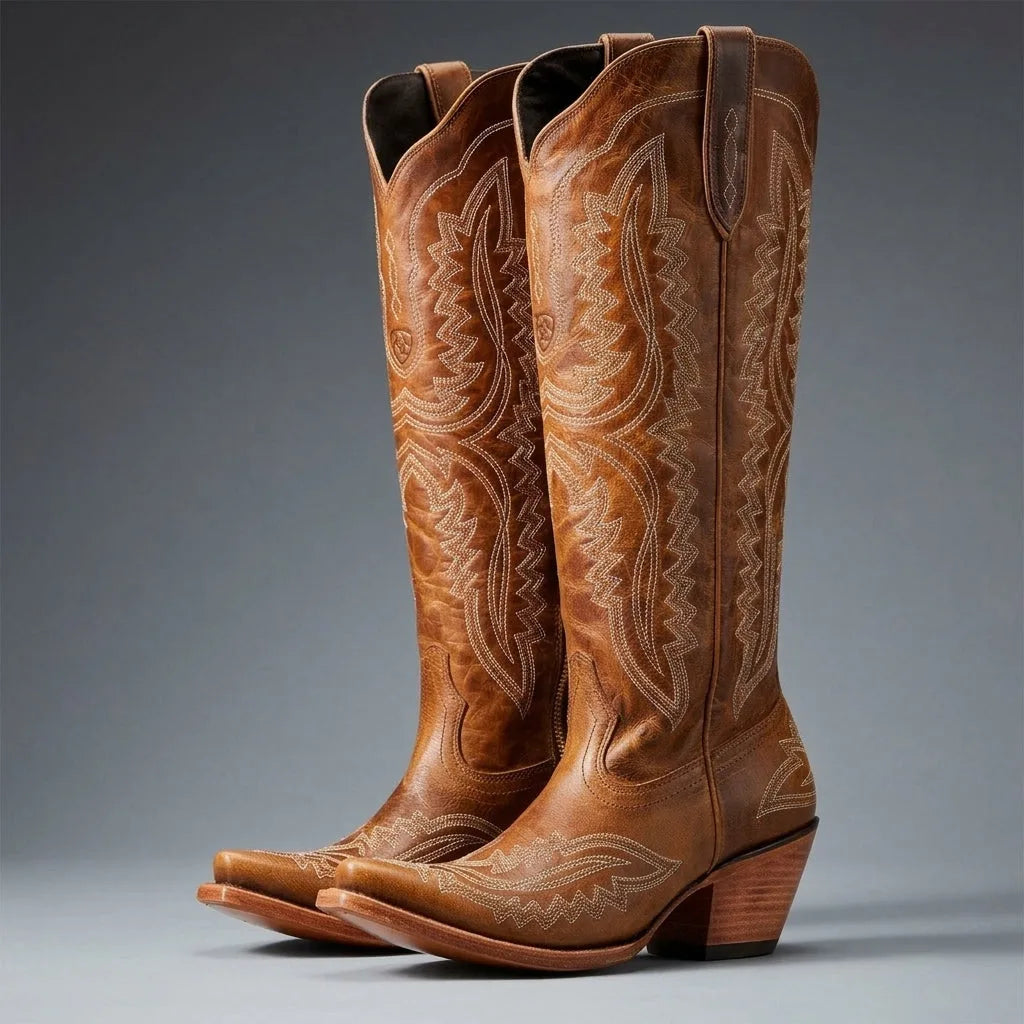 Side view of tall brown leather cowboy boots with cream western stitching and a stacked block heel, shown as a pair