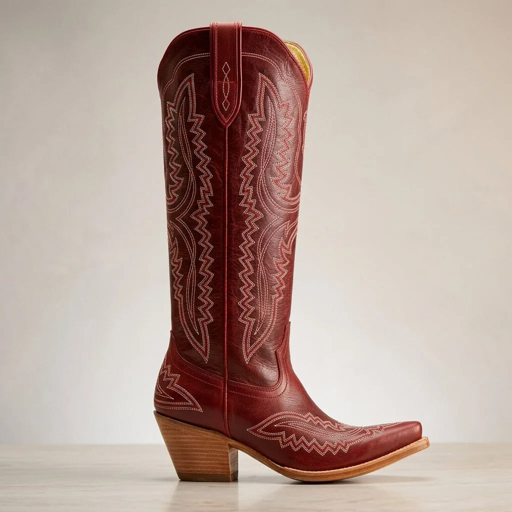 Side view of a deep red leather cowboy boot with cream western stitching and a curved block heel