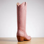 Close-up of a pink leather cowboy boot heel and sole detail against a neutral backdrop
