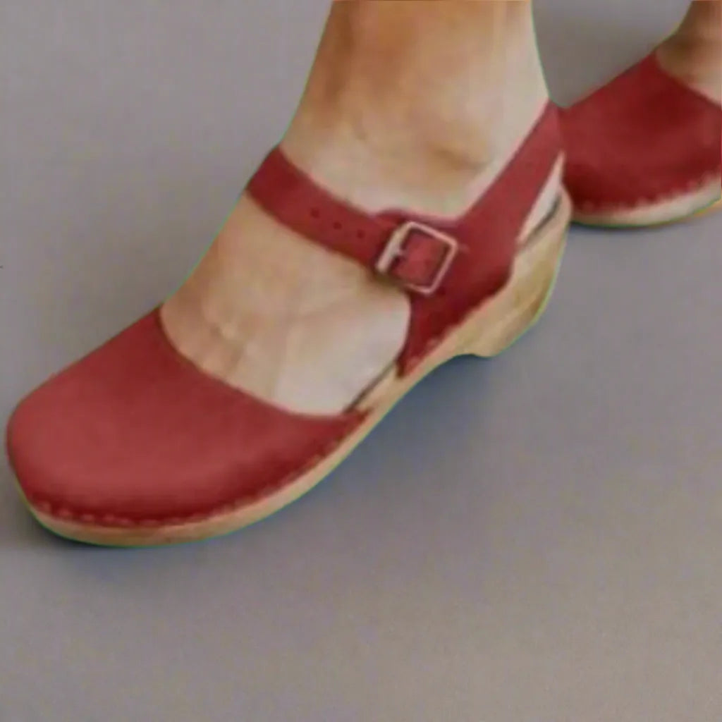 Close-up front view of a red suede clog sandal with buckle strap and visible stitched wooden sole