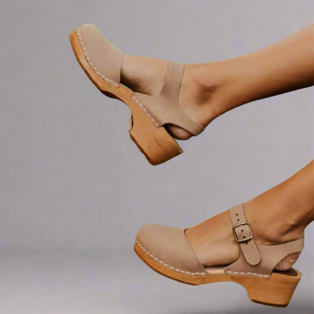 Beige suede clog sandals shown from the side, one with buckle strap closed and one open-back angle