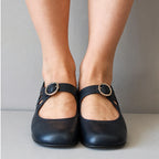 Front-on view of navy leather mary jane flats on both feet, showing the silver buckle and rounded toe