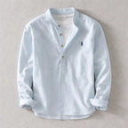 Pale blue henley shirt with stand collar and wooden-style buttons, sleeves cuffed, shown flat on a neutral backdrop