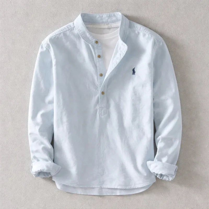 Pale blue henley shirt with stand collar and wooden-style buttons, sleeves cuffed, shown flat on a neutral backdrop