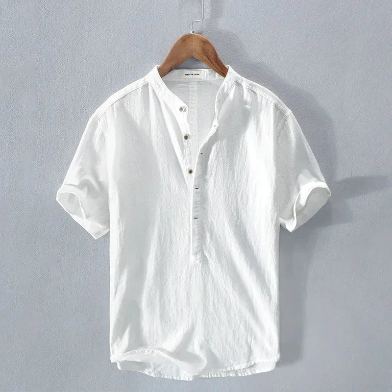 White short-sleeve linen-cotton shirt with stand collar and button placket, hanging flat against a plain grey backdrop