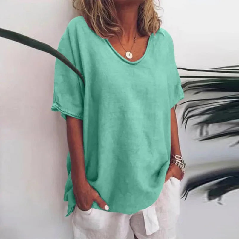 Woman wearing the relaxed-fit t-shirt in green, with a plant visible in the background