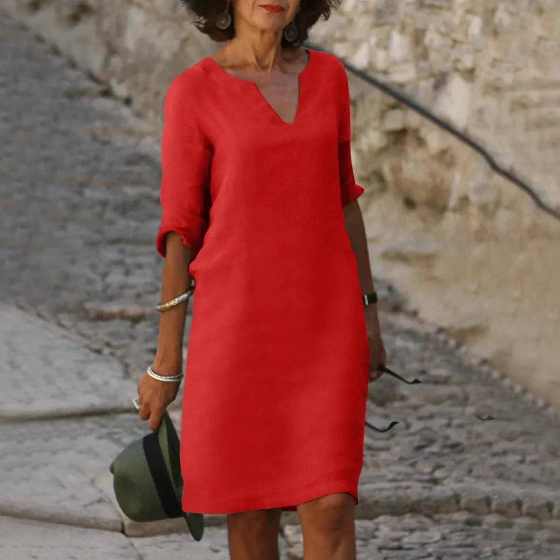 Red textured linen-look dress with half sleeves and above-knee hem, standing on cobblestones