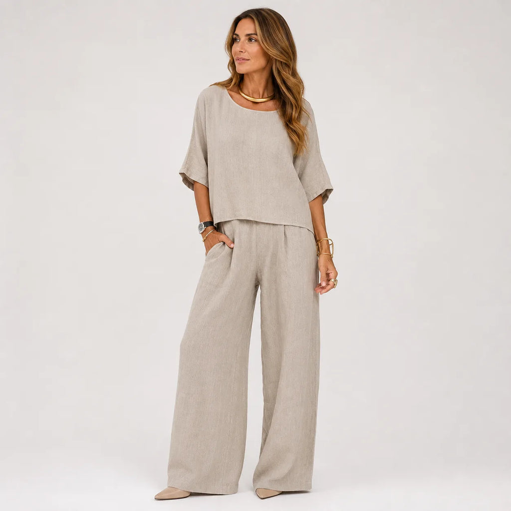 Woman wearing an oversized grey marle linen-look top and wide leg pants set with gold jewellery, styled with pointed flats