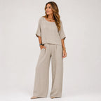 Woman wearing an oversized grey marle linen-look top and wide leg pants set with gold jewellery, styled with pointed flats