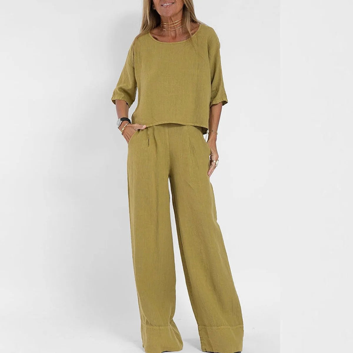 Woman wearing the two-piece set in mustard yellow, boxy cropped top and wide leg pants with pockets